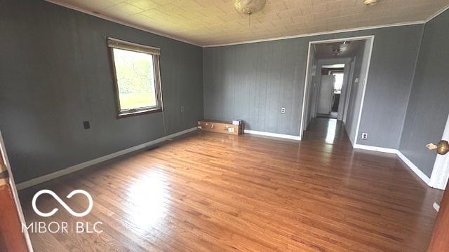 empty room featuring baseboards, ornamental molding, and wood finished floors