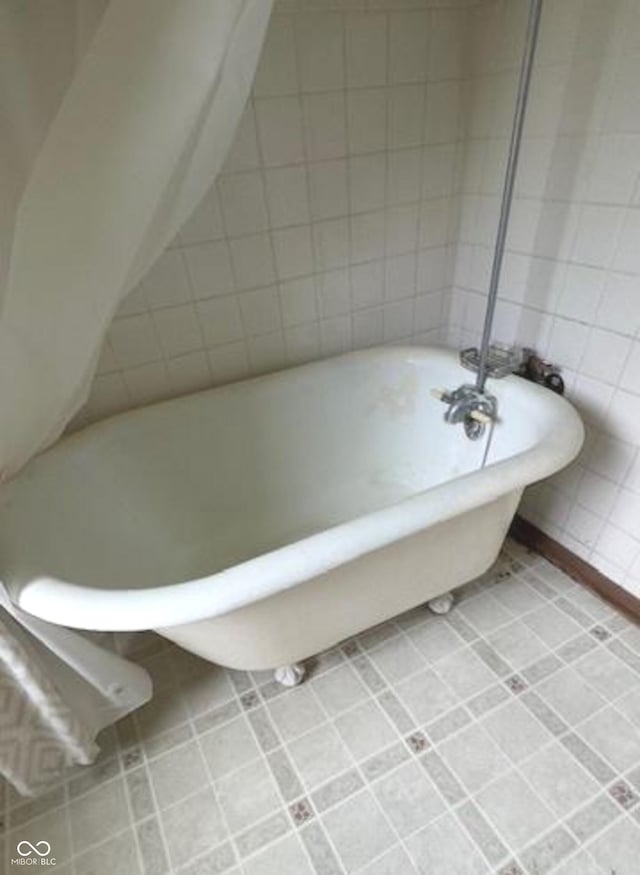 full bath featuring tile patterned flooring, a freestanding tub, and tile walls
