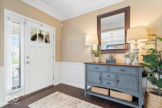 foyer entrance featuring crown molding, dark wood finished floors, and a wainscoted wall