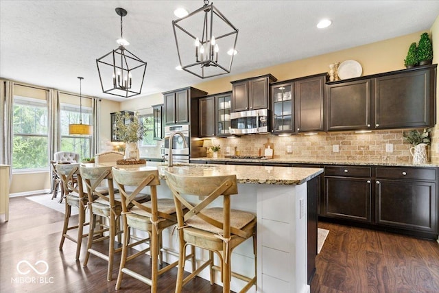 kitchen with dark wood-style flooring, backsplash, dark brown cabinets, and stainless steel appliances