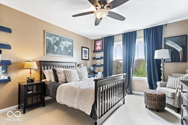bedroom featuring a textured ceiling, baseboards, light colored carpet, and ceiling fan