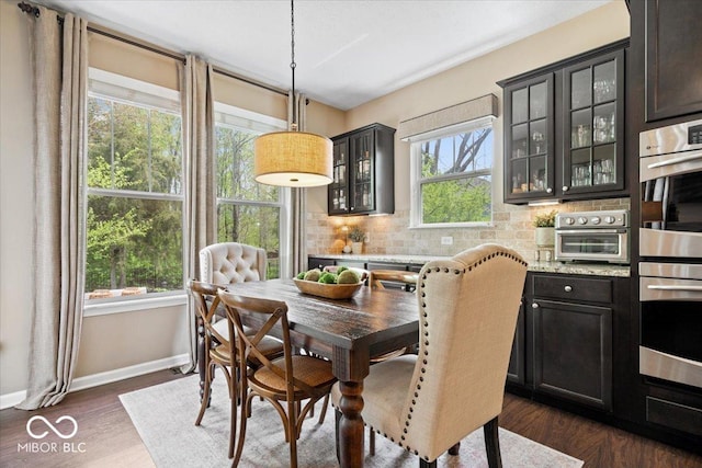 dining area with a toaster, baseboards, and dark wood-style flooring