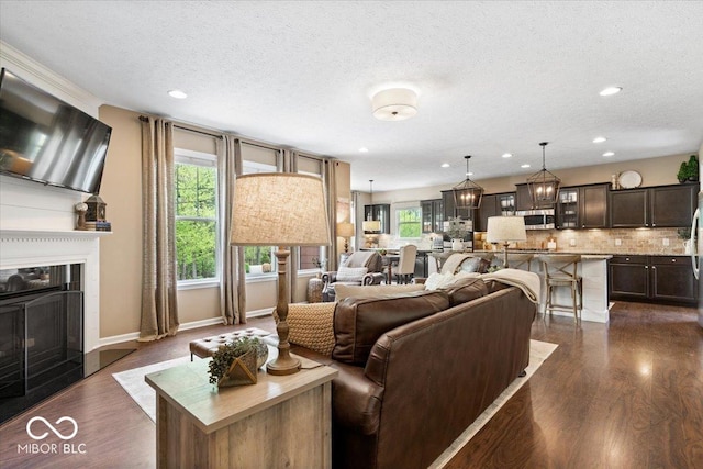 living room with a fireplace with raised hearth, a textured ceiling, recessed lighting, and dark wood-style floors
