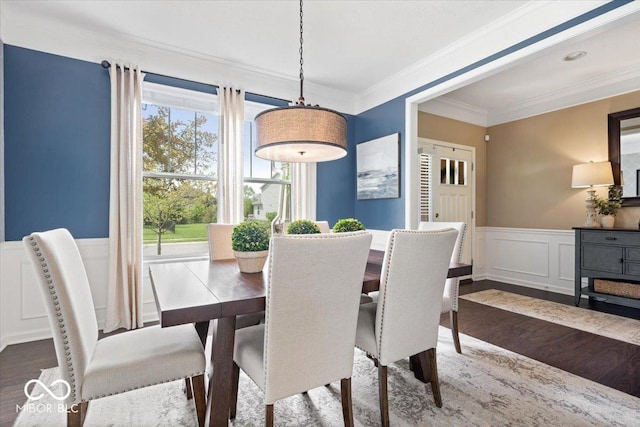 dining area featuring crown molding, wainscoting, a decorative wall, and dark wood-style floors