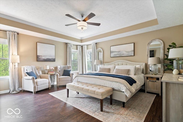 bedroom with a textured ceiling, dark wood-style floors, and a tray ceiling