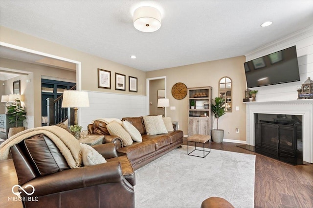 living area with recessed lighting, a fireplace with flush hearth, wainscoting, and wood finished floors