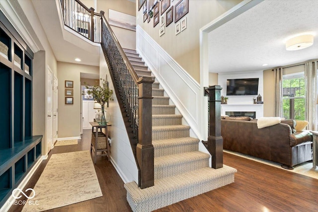 stairs with a glass covered fireplace, baseboards, recessed lighting, and wood finished floors