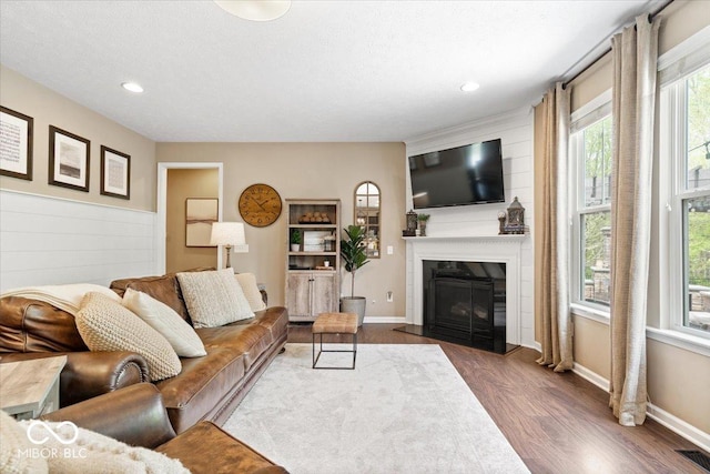 living area with a healthy amount of sunlight, a fireplace, wood finished floors, and visible vents
