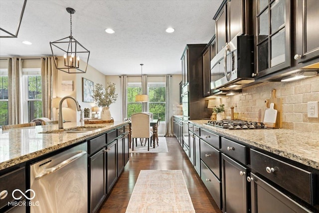 kitchen with a sink, appliances with stainless steel finishes, plenty of natural light, and light stone counters