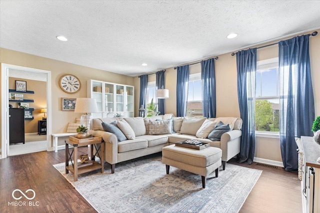 living area with a textured ceiling, recessed lighting, baseboards, wood finished floors, and visible vents