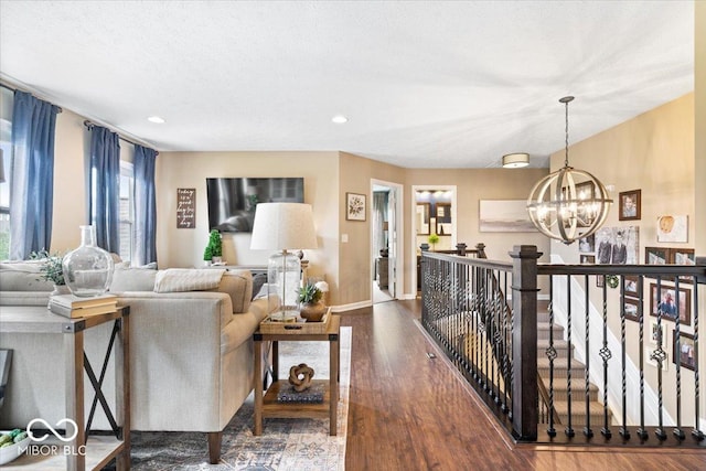 living area with recessed lighting, baseboards, an inviting chandelier, and wood finished floors