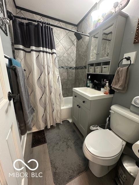 bathroom with toilet, wood finished floors, shower / bath combo, and vanity
