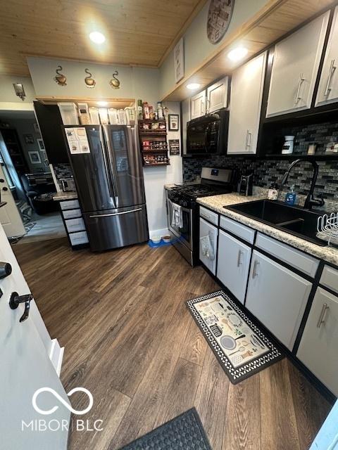 kitchen featuring freestanding refrigerator, black microwave, dark wood-style floors, stainless steel range with gas cooktop, and a sink