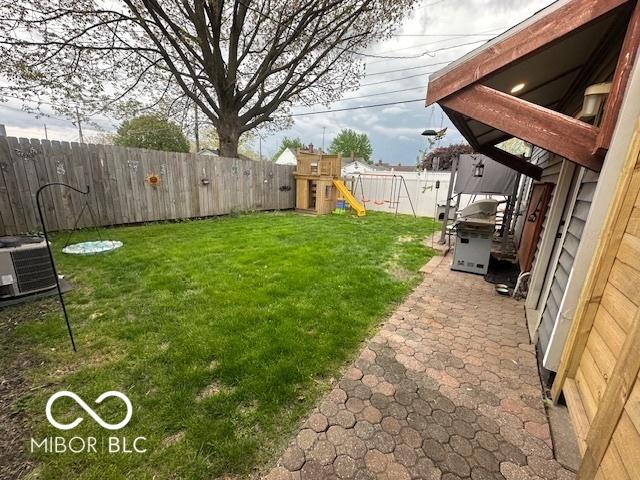 view of yard with a patio, cooling unit, a fenced backyard, and a playground