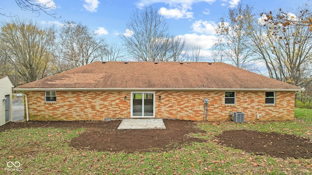 back of property with brick siding, cooling unit, roof with shingles, and a patio