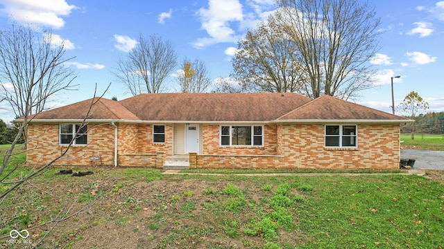 ranch-style home with brick siding, a shingled roof, and a front lawn