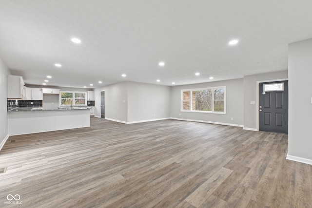 unfurnished living room featuring recessed lighting, baseboards, a wealth of natural light, and light wood-style floors