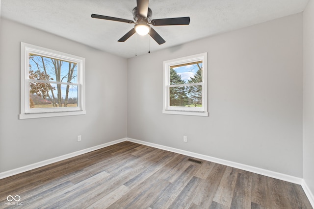 unfurnished room with plenty of natural light, baseboards, wood finished floors, and visible vents