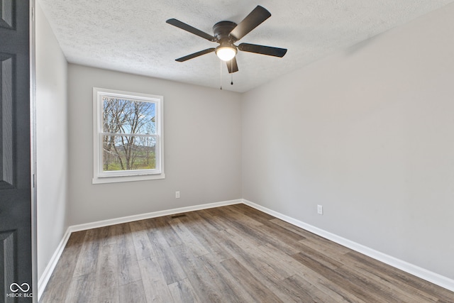 spare room with a textured ceiling, ceiling fan, baseboards, and wood finished floors