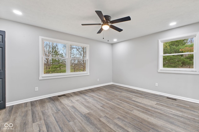 empty room with a ceiling fan, visible vents, and wood finished floors