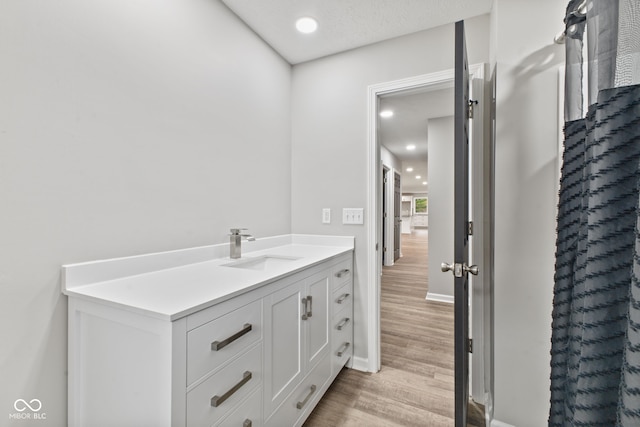 bathroom featuring vanity, baseboards, recessed lighting, and wood finished floors