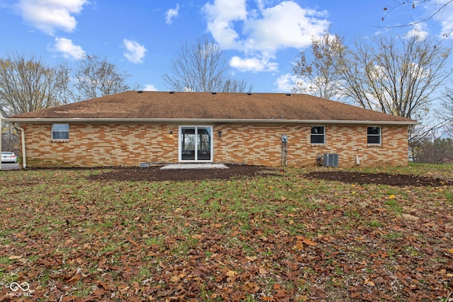 rear view of property with brick siding, central AC, and roof with shingles