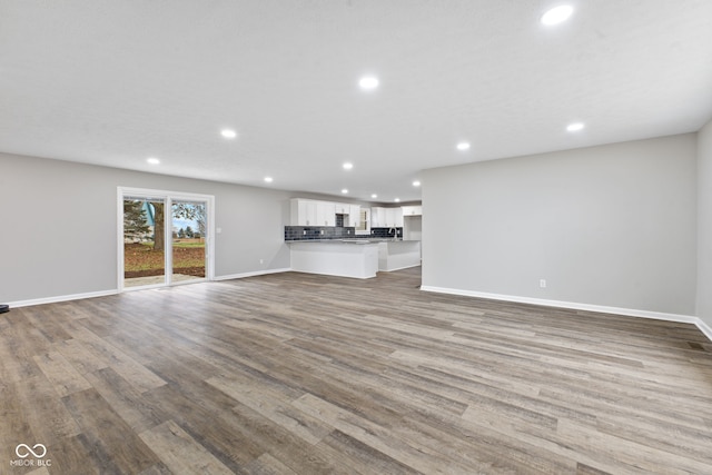 unfurnished living room with baseboards, recessed lighting, and wood finished floors