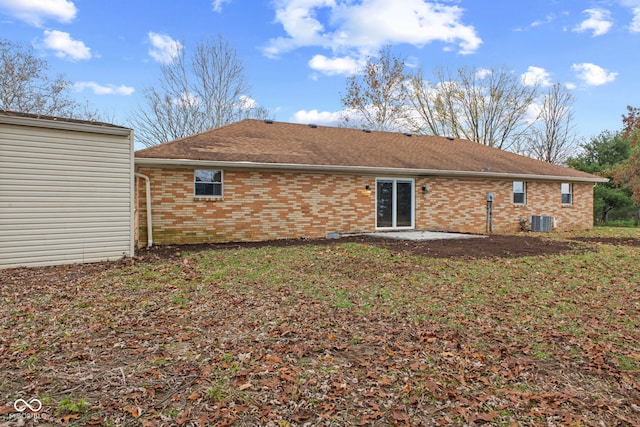 back of house with central air condition unit, brick siding, and a shingled roof