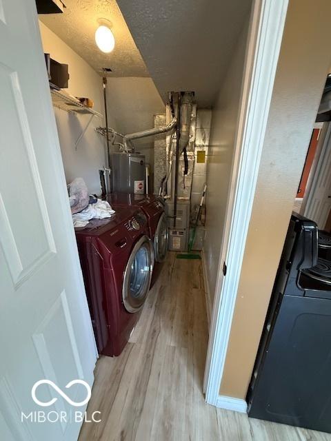 laundry area featuring heating unit, wood finished floors, a textured ceiling, gas water heater, and independent washer and dryer