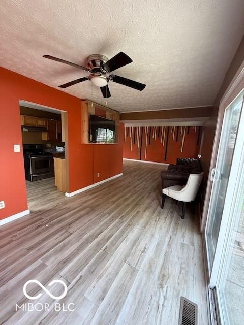 unfurnished living room featuring a ceiling fan, a textured ceiling, visible vents, and light wood-type flooring