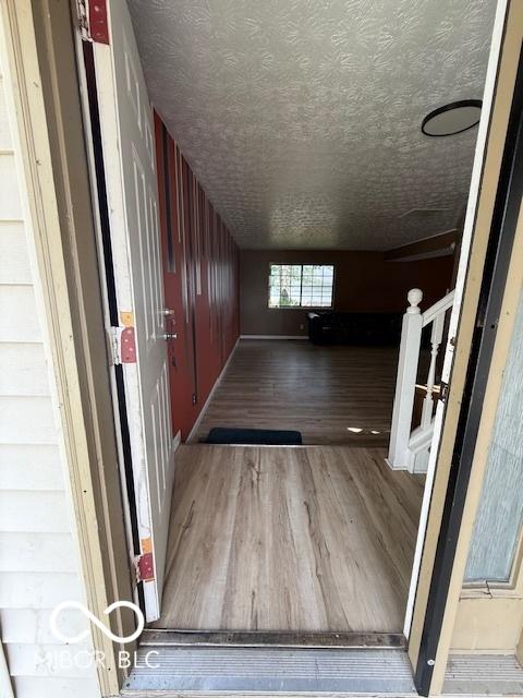 hall featuring a textured ceiling, wood finished floors, and stairway