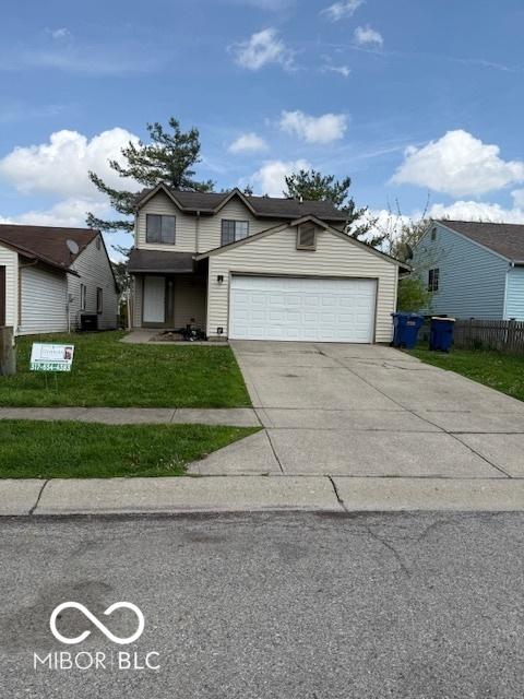 traditional-style house with an attached garage, a front lawn, fence, and concrete driveway
