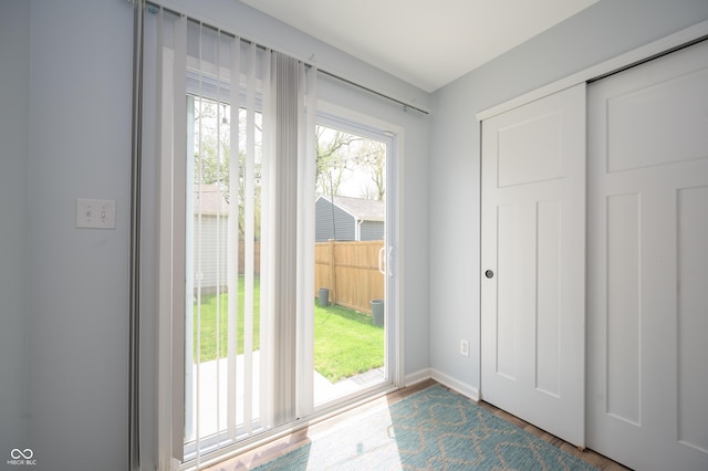 doorway to outside featuring baseboards and wood finished floors
