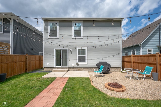 rear view of house with a patio, a fenced backyard, a fire pit, and a yard