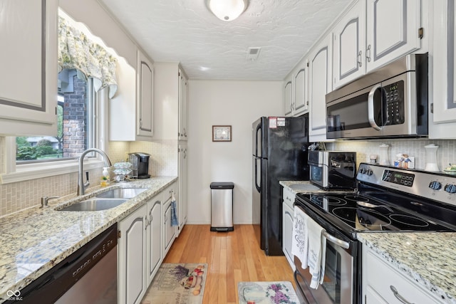 1030 Stratford Hall Unit 17-3, Indianapolis, IN 46260 - kitchen featuring stainless steel appliances, a sink, tasteful backsplash, light wood-style flooring, and a textured ceiling