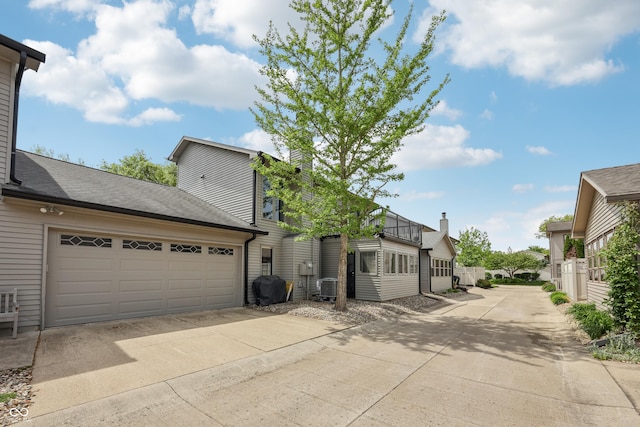 1030 Stratford Hall Unit 17-3, Indianapolis, IN 46260 - view of property exterior with driveway, cooling unit, a chimney, and a garage