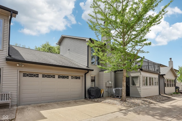 1030 Stratford Hall Unit 17-3, Indianapolis, IN 46260 - view of front of home with a chimney, a balcony, cooling unit, concrete driveway, and a garage