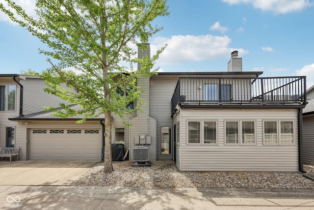 1030 Stratford Hall Unit 17-3, Indianapolis, IN 46260 - rear view of property with a balcony, a chimney, driveway, an attached garage, and central AC