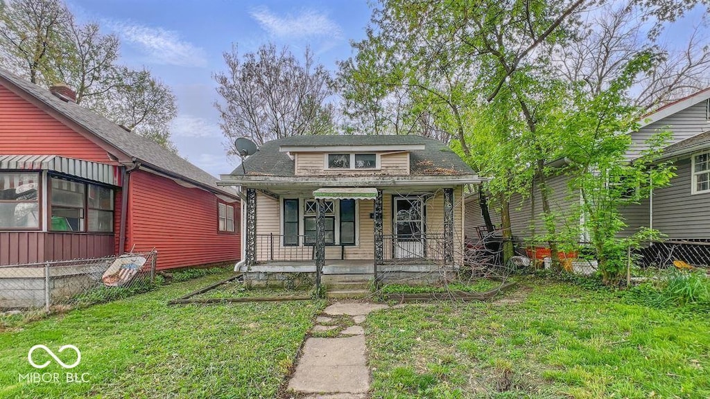 bungalow with a porch, fence, and a front lawn