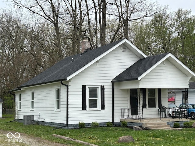 ranch-style home with a porch, a chimney, a shingled roof, and a front lawn