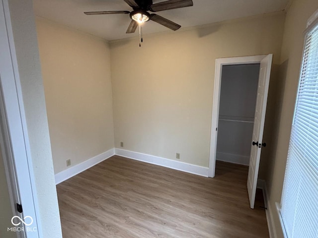 unfurnished bedroom featuring baseboards, wood finished floors, a spacious closet, and a closet
