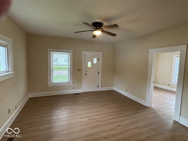 entrance foyer featuring visible vents, wood finished floors, baseboards, a textured ceiling, and a ceiling fan