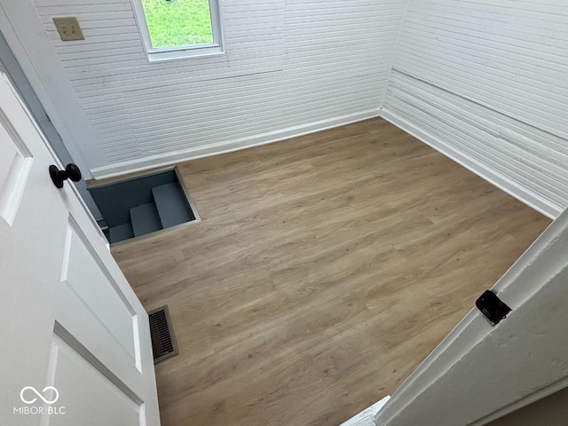 spare room featuring baseboards, visible vents, and wood finished floors