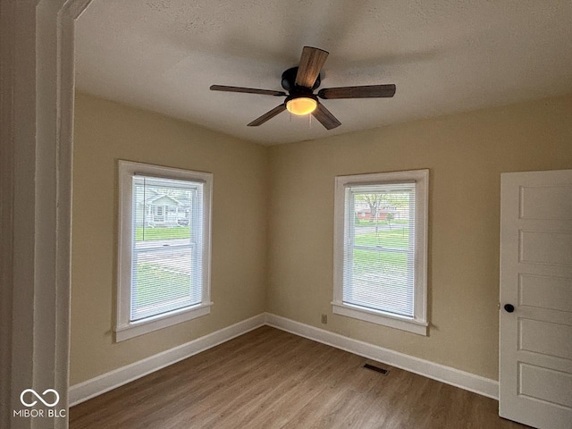 spare room featuring baseboards, wood finished floors, and a healthy amount of sunlight