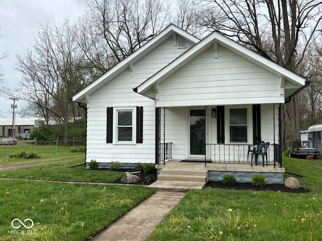 bungalow-style home featuring fence, covered porch, and a front lawn