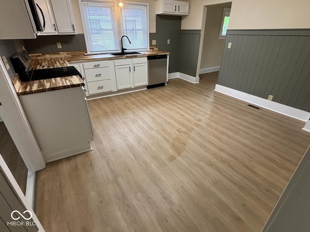 kitchen with butcher block countertops, a sink, white cabinetry, and appliances with stainless steel finishes
