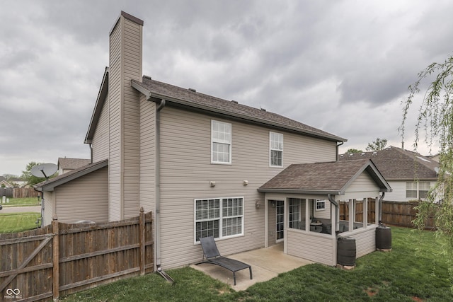 rear view of property featuring a lawn, a fenced backyard, a patio area, and a chimney