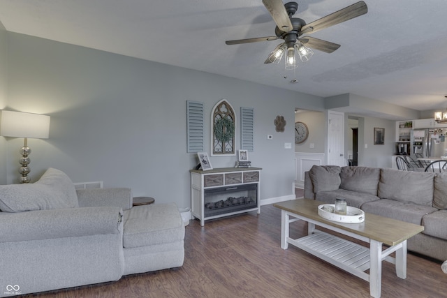 living room with baseboards, ceiling fan with notable chandelier, wood finished floors, and visible vents