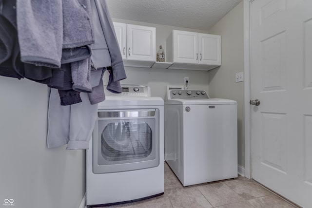 laundry area with a textured ceiling, baseboards, cabinet space, and independent washer and dryer