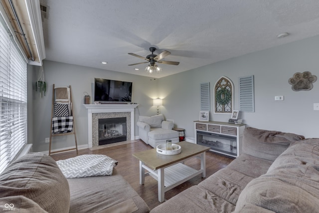 living area with a fireplace with flush hearth, wood finished floors, baseboards, recessed lighting, and a ceiling fan